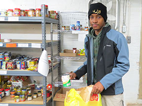 A young man packs canned goods into a bag.