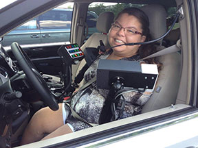 A young woman in the driver's seat of a heavily modified minivan.
