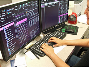 A woman types on a keyboard. In front of her are two oversized monitors displaying enlarged text in high contrast.