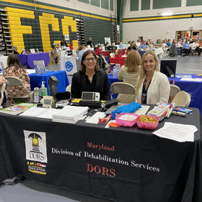 Two women at a table at a resource fair.