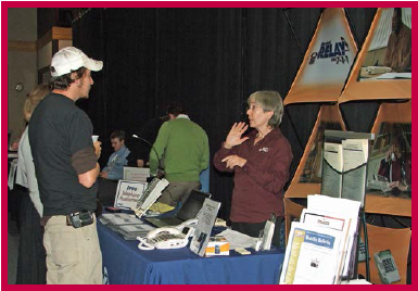 A man and a woman at a conference exhibit table.
