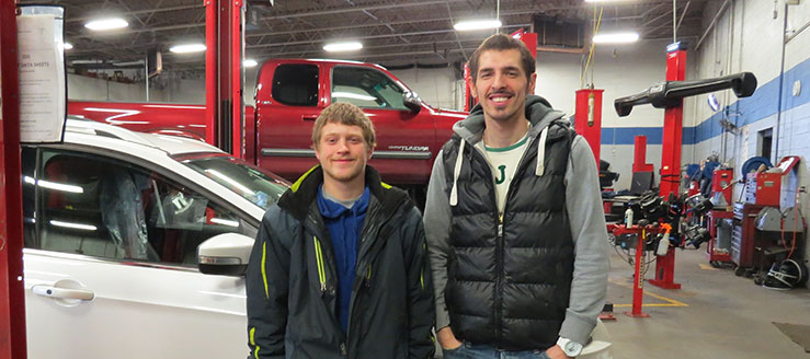Nick McClain and Emre Sen standing in the automobile repair garage at the SEARS Auto Center.