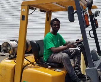A young man driving a forklift.