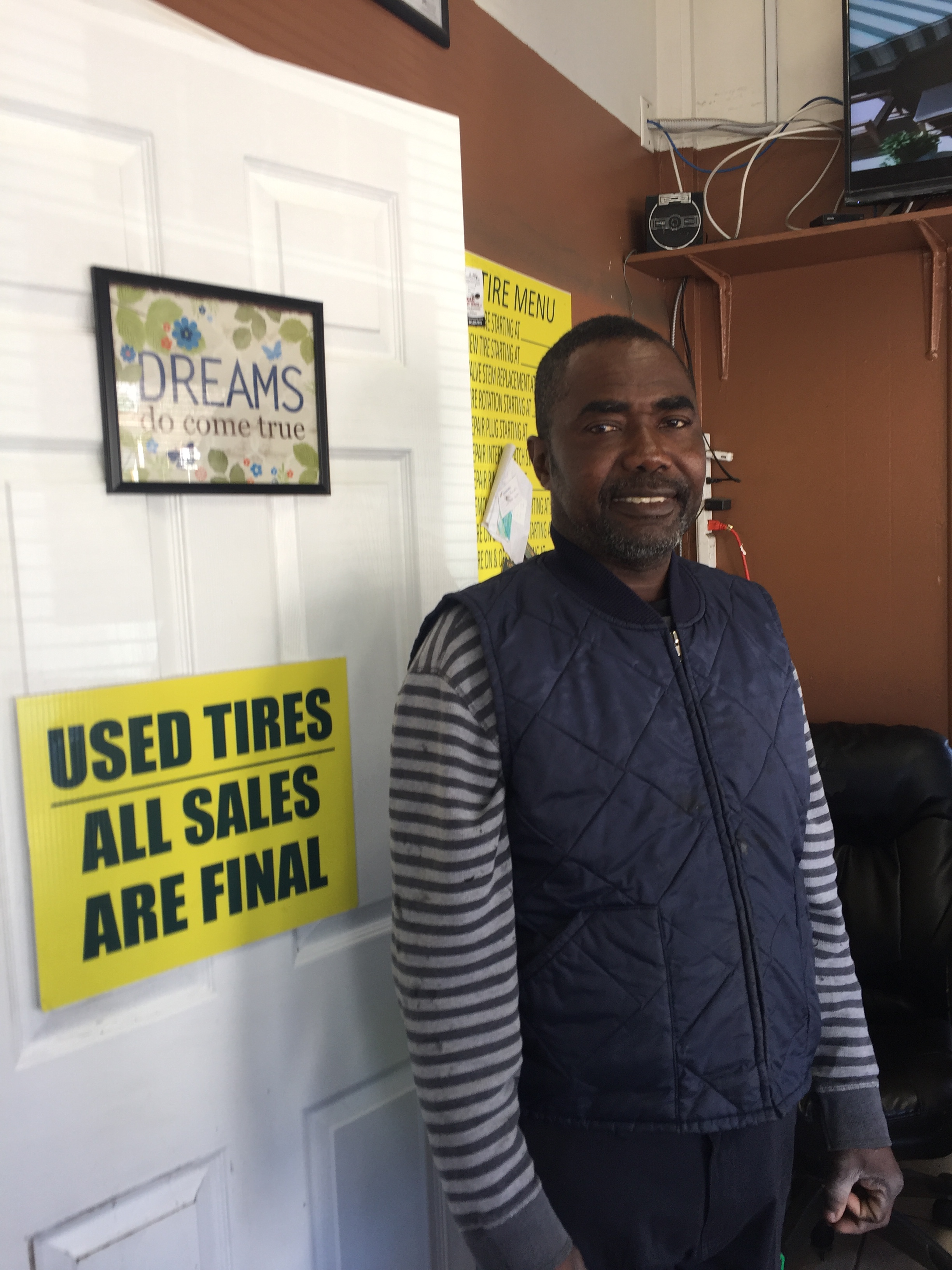 Bright Dzansi in his office, next to sign that reads: Dreams do come true>
