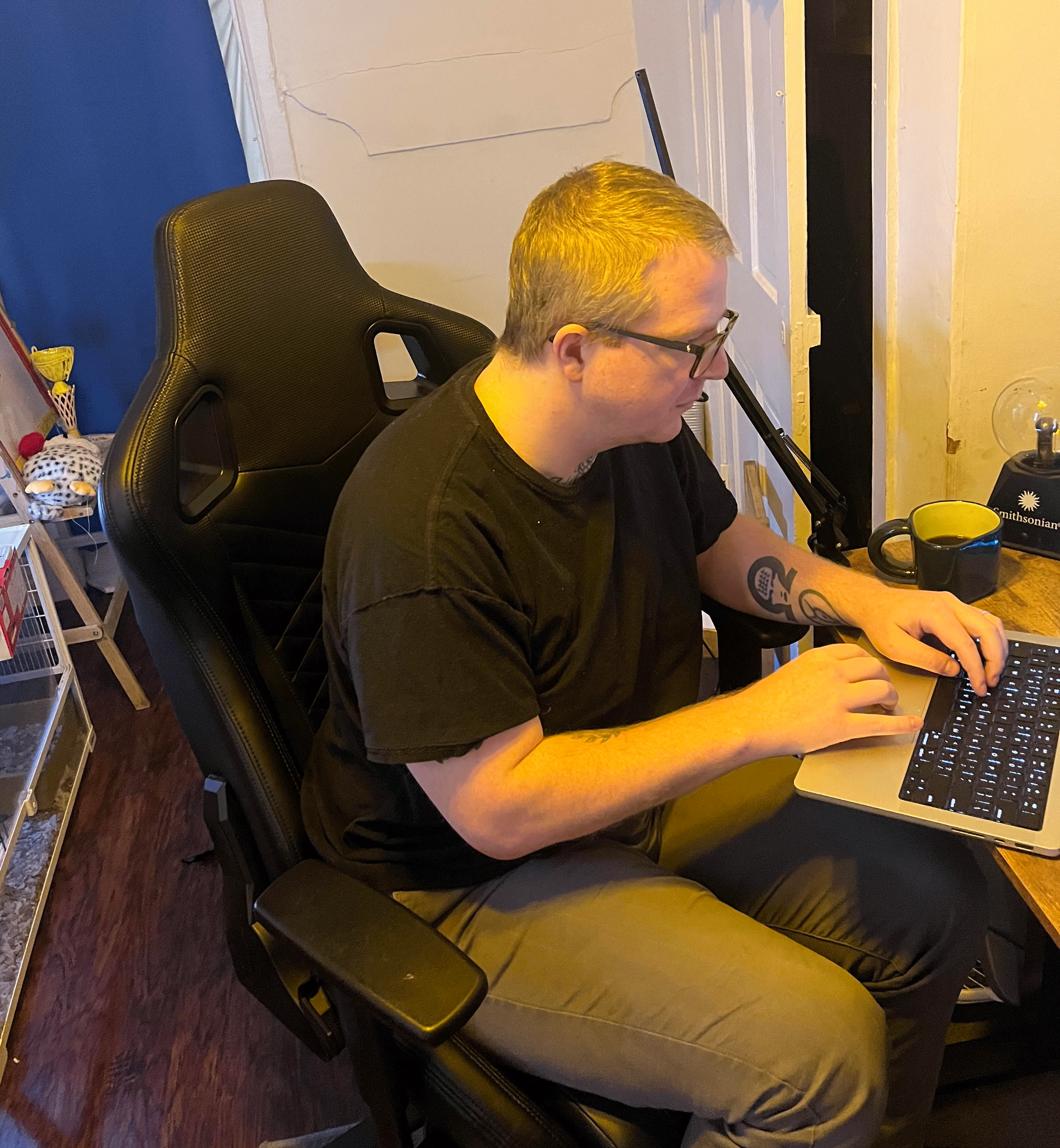Jake, sitting in an office chair, working at his laptop.