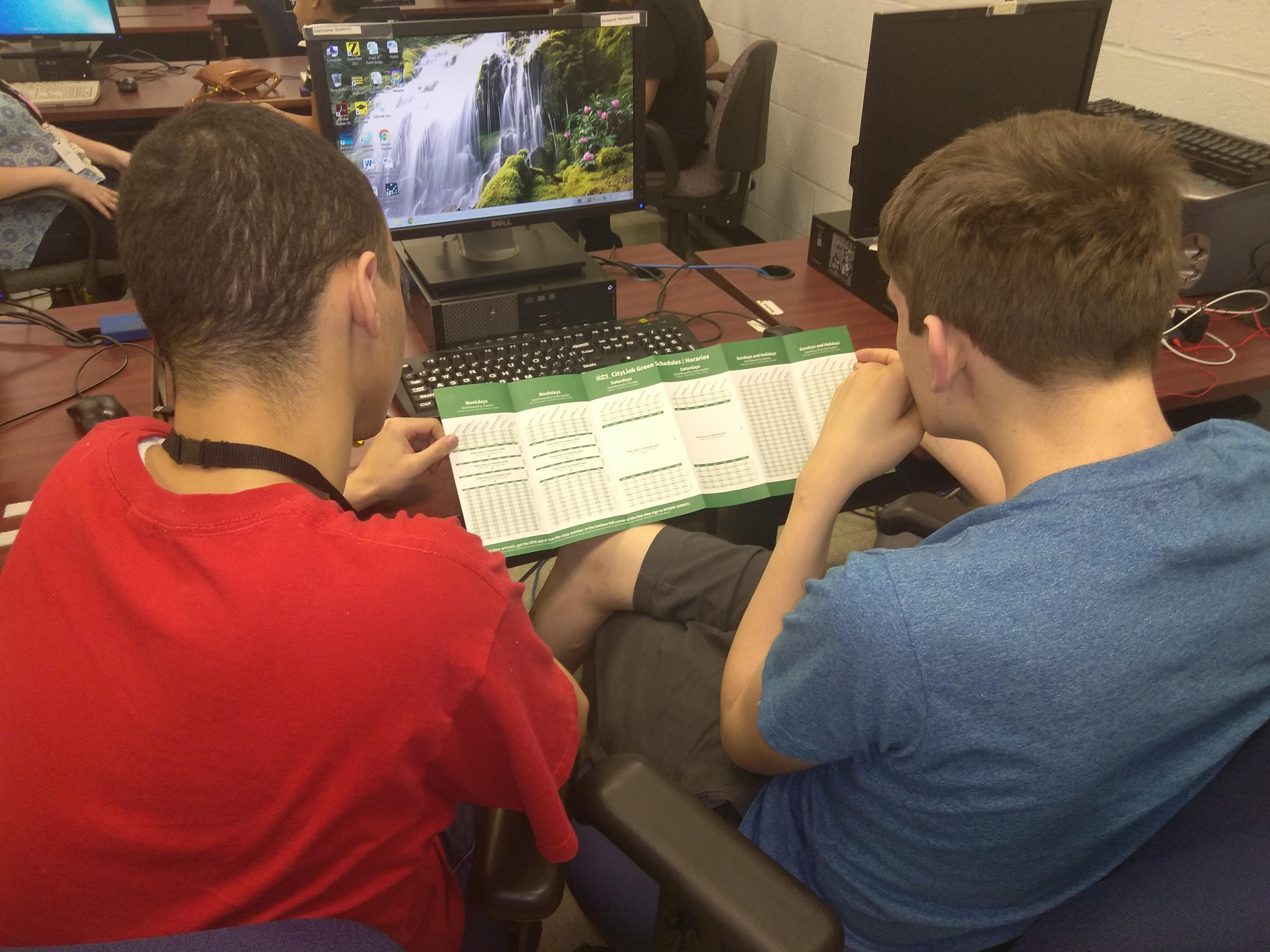 Two Travel Training students looking at a bus route schedule.
